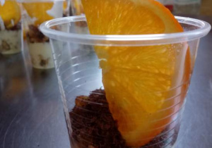 Deser owsiany ozdobiony plastrem z pomarańczy w plastykowym kubeczku